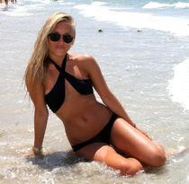 Slender blonde teen posing in little swimsuit near a pool