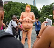 Funny people photographing with a statue of nude Trump