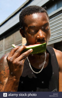 Young black man eating watermelon on the street Stock Photo: